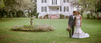 Portrait of groom with the bride in strapless formal wedding gown by posing in front of the historic Hopsewee Plantation home.
